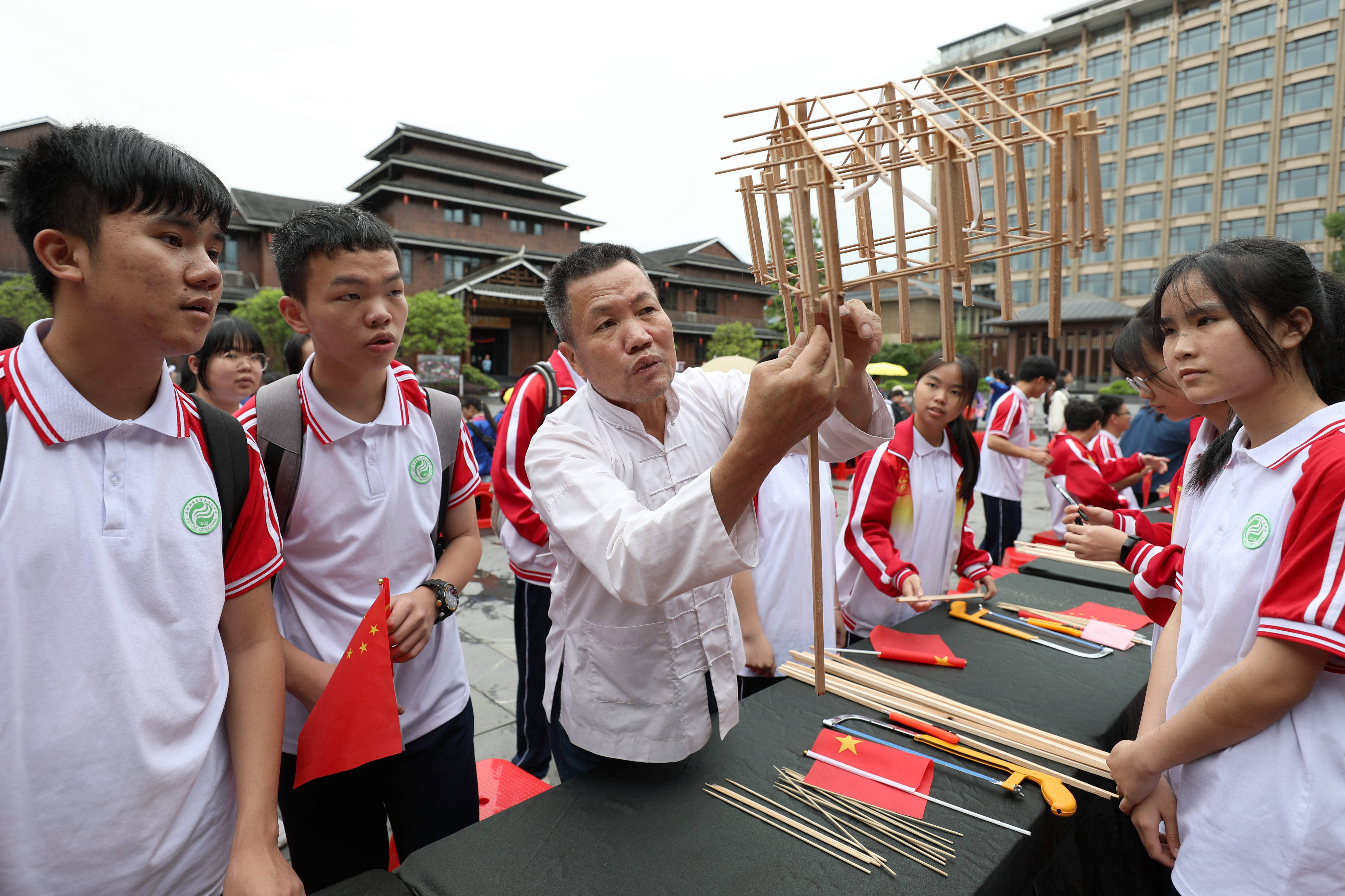 5月17日,在三江侗族自治县博物馆前,非遗传承人杨似玉在指导学生拼装侗族木构建筑模型。.jpg