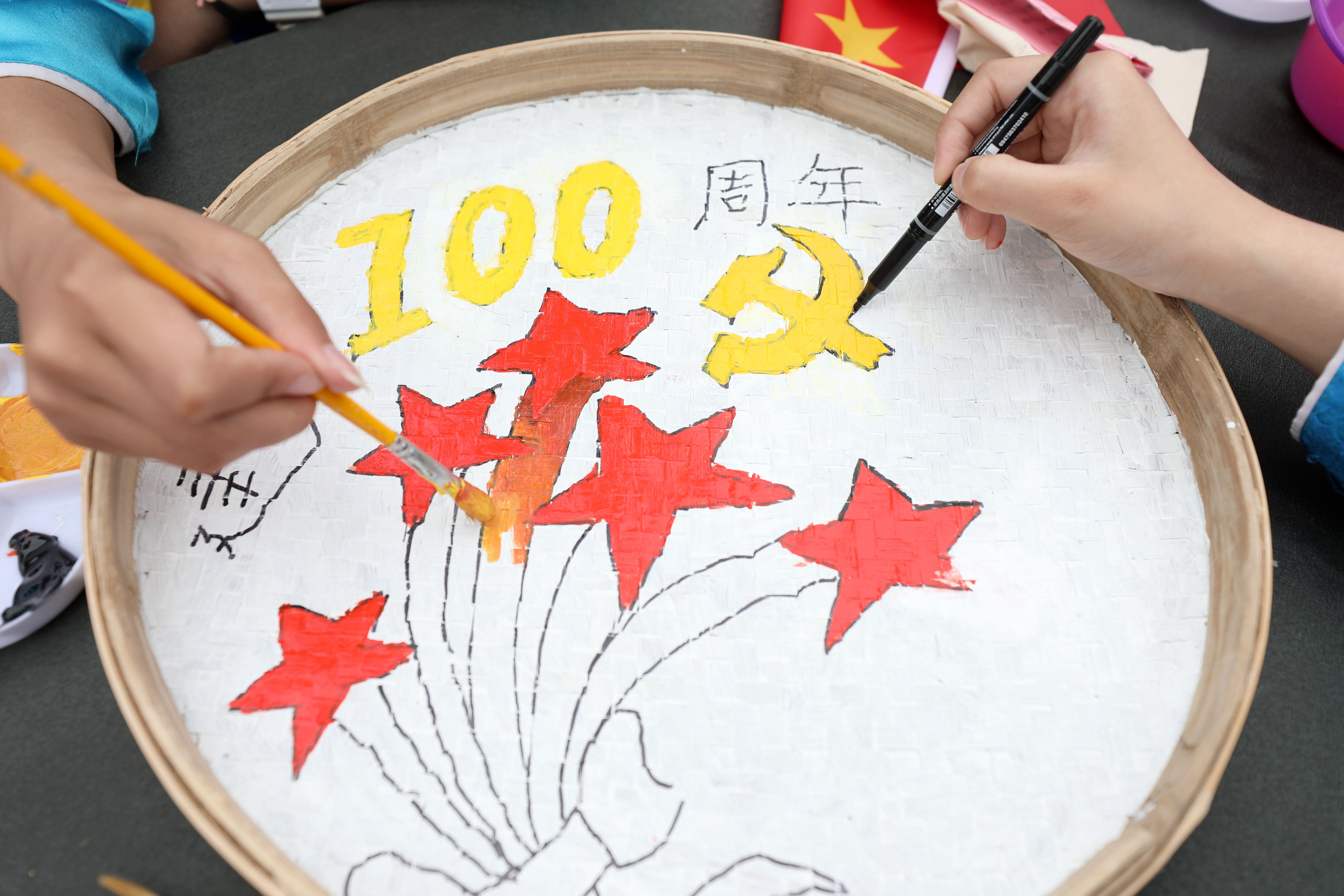 5月17日,在三江侗族自治县博物馆前,两名学生在画党史题材侗族簸箕画。.jpg